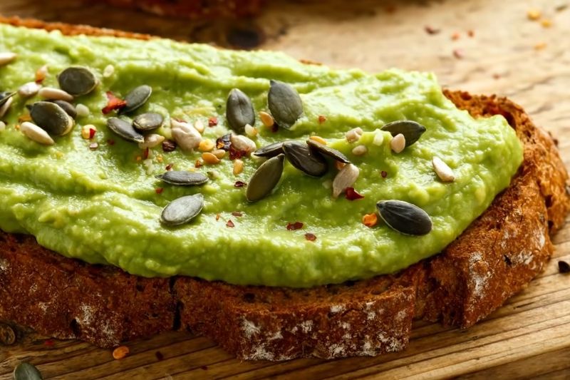Whole grain toast topped with avocado spread and seeds