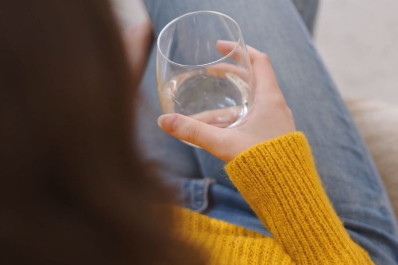 Person holding a glass of water while resting
