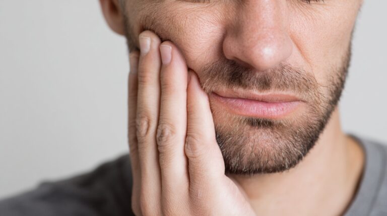 Man holding his cheek, indicating toothache or dental pain